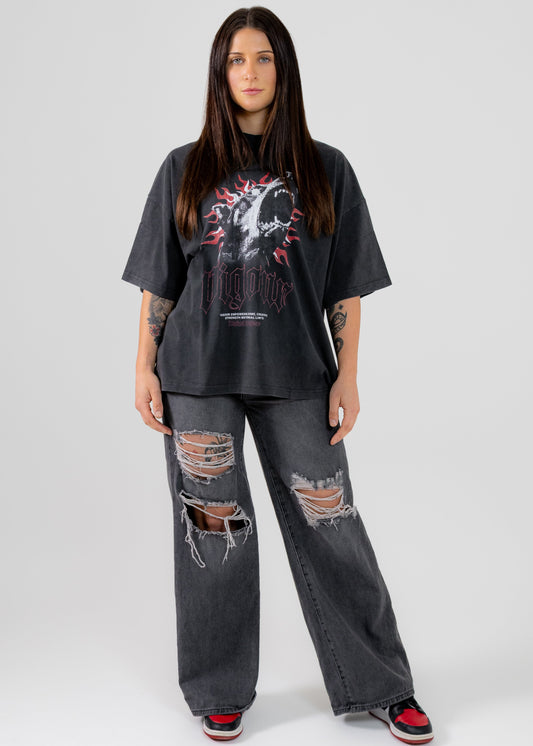 Person wearing a black oversized t-shirt and ripped jeans on a white background