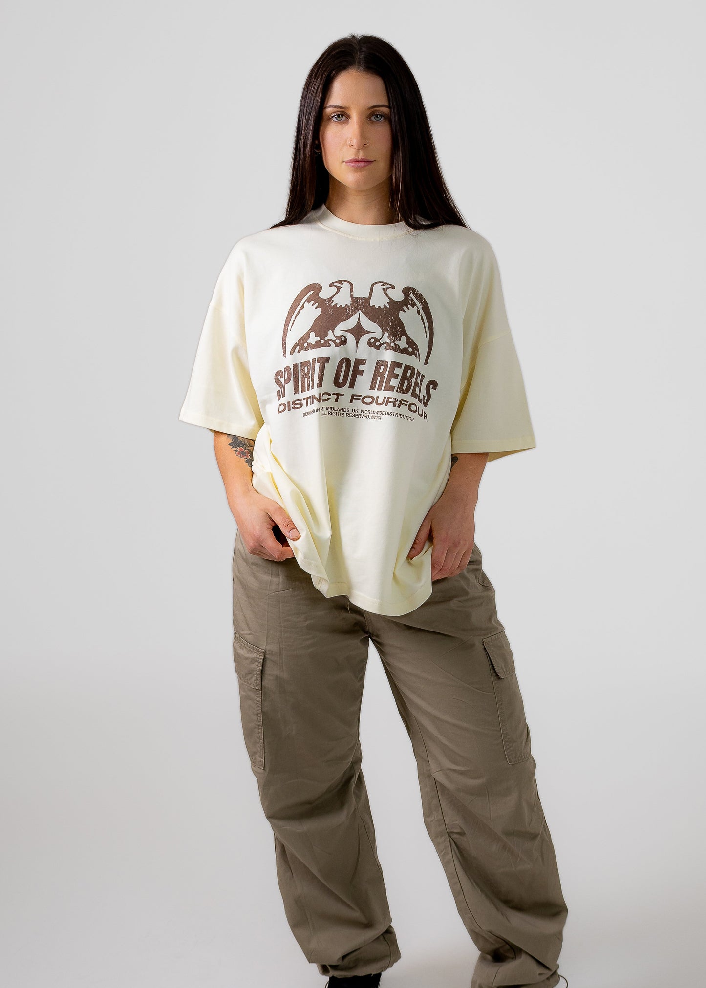 Person wearing a cream t-shirt with a graphic design and text, standing against a plain background