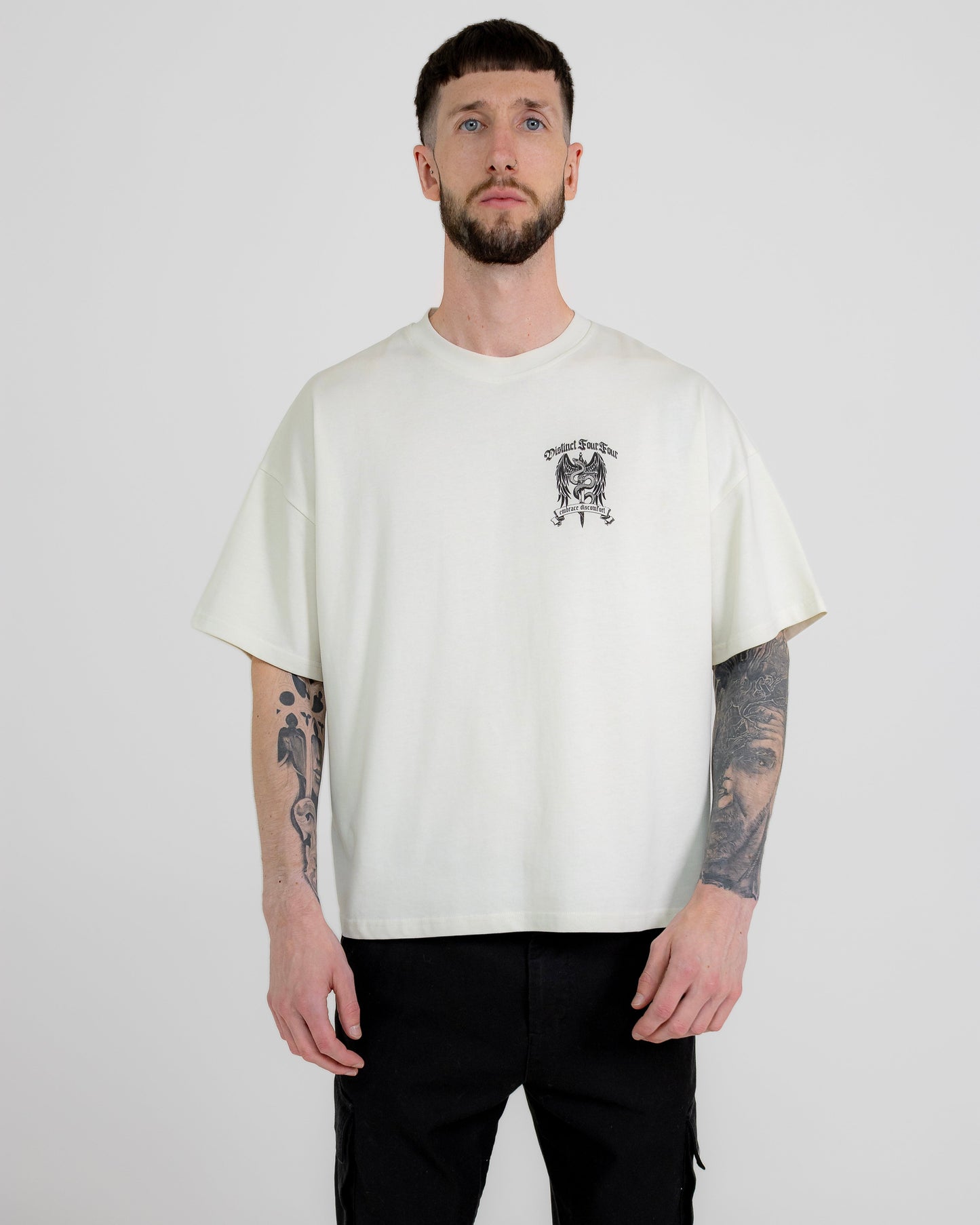 A male model wearing a white short-sleeved T-shirt with a graphic print in the center, standing against a plain background.
