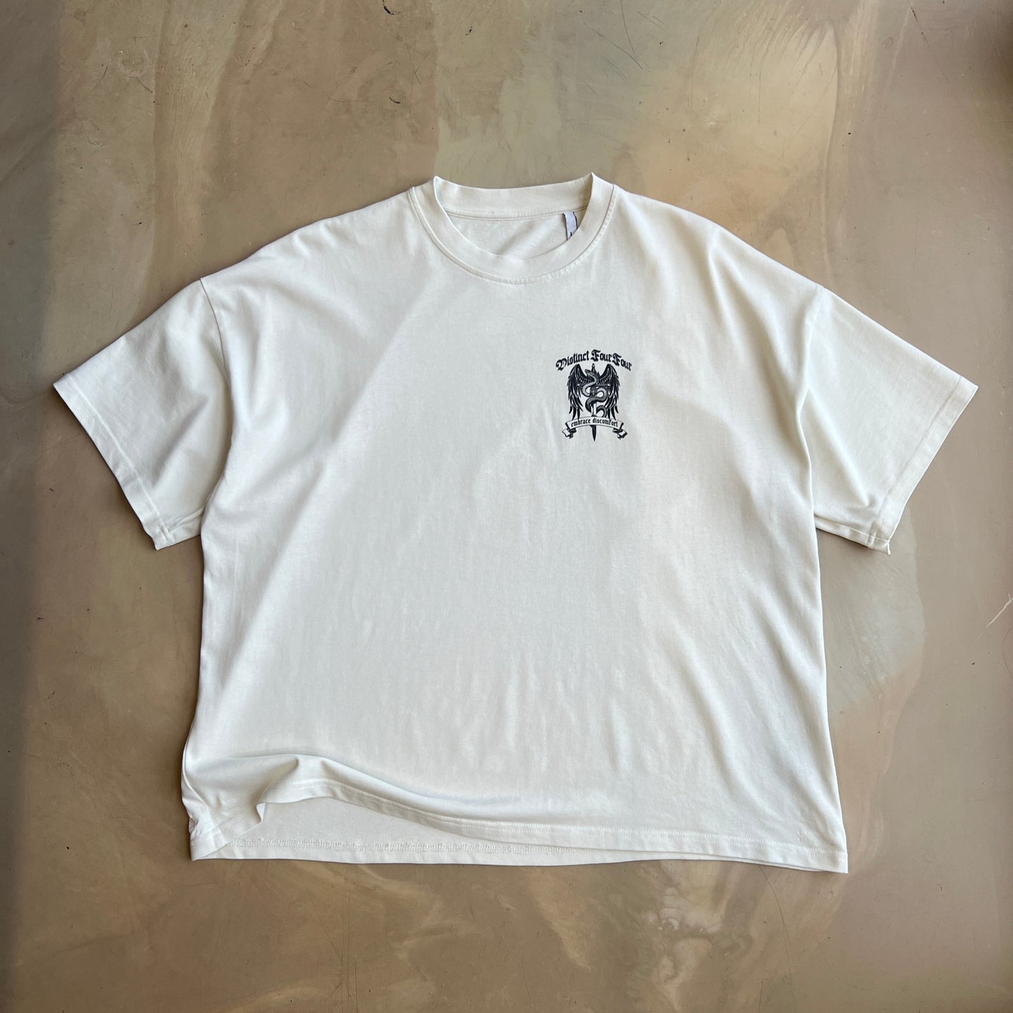 Vintage White t-shirt with a small black graphic on a concrete surface
