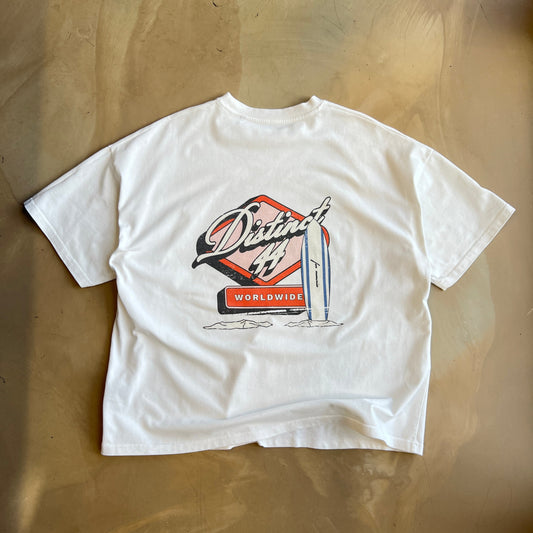 White graphic t-shirt with a small logo on a concrete surface