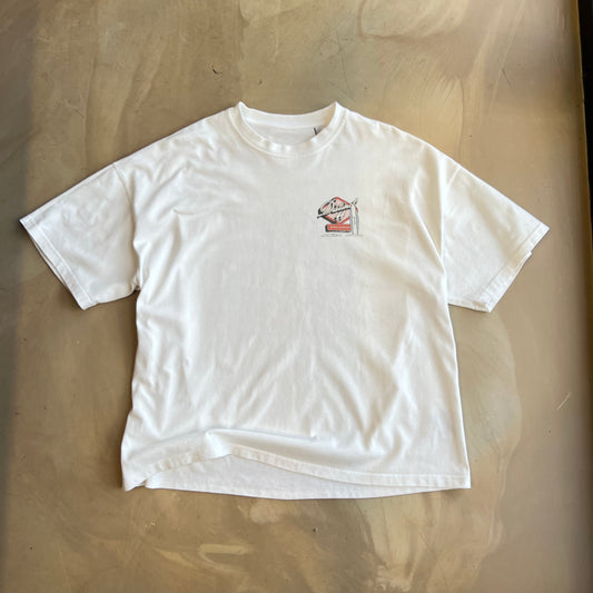 White graphic t-shirt with a small logo on a concrete surface