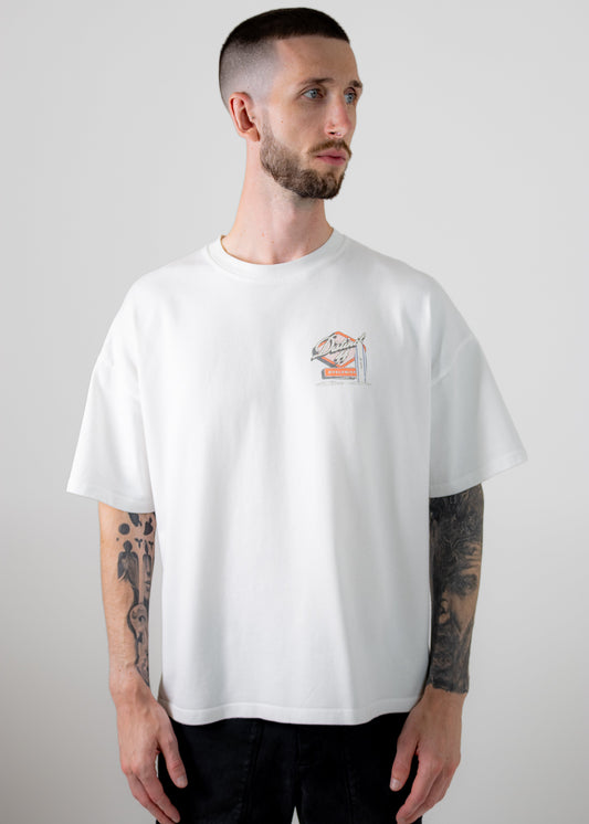 Man wearing a white t-shirt with a small graphic on a plain background