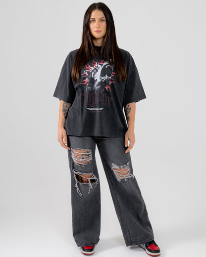 Person wearing a black oversized t-shirt and ripped jeans on a white background