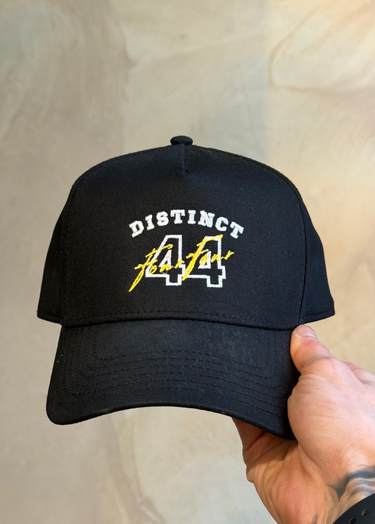 Black cap with 'Distinct 44' text held by a hand against a neutral background