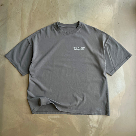 Pigment Grey t-shirt with a logo on a concrete surface