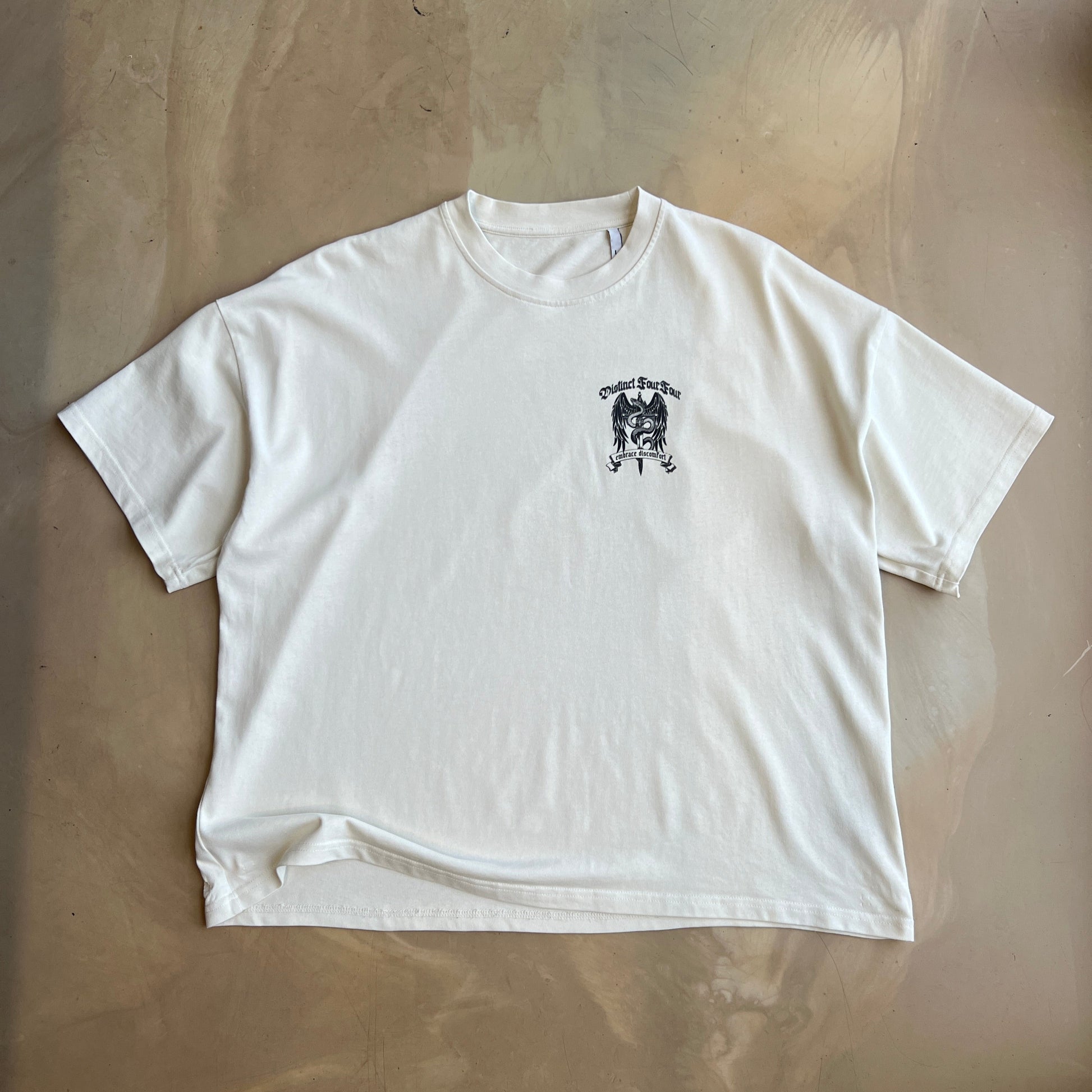 Vintage White t-shirt with a small black graphic on a concrete surface