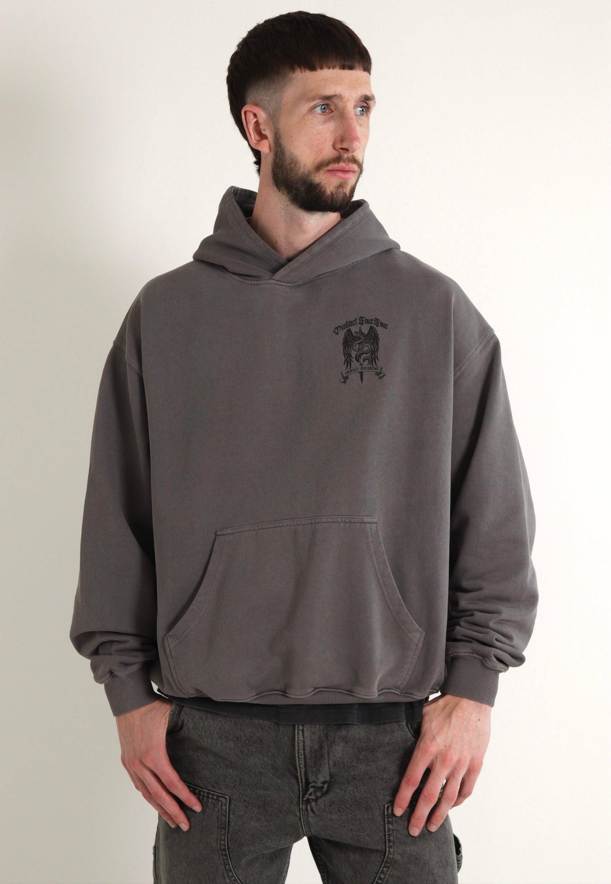 Man wearing a gray hoodie with a logo on a plain background
