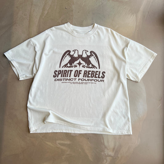 Cream t-shirt with brown text and graphics on a concrete surface