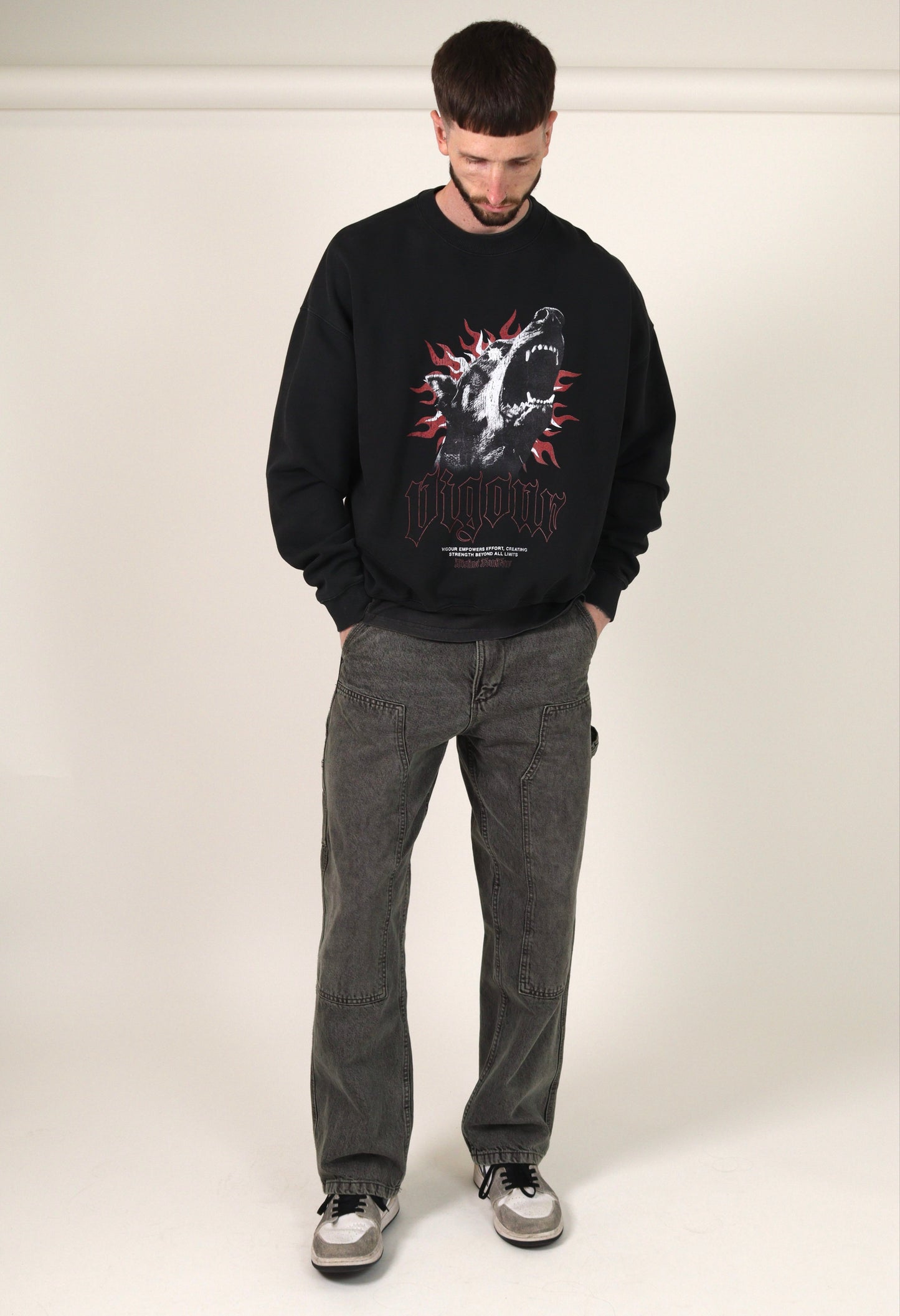 Person wearing a  vintage black sweatshirt with a graphic design and grey jeans on a white background