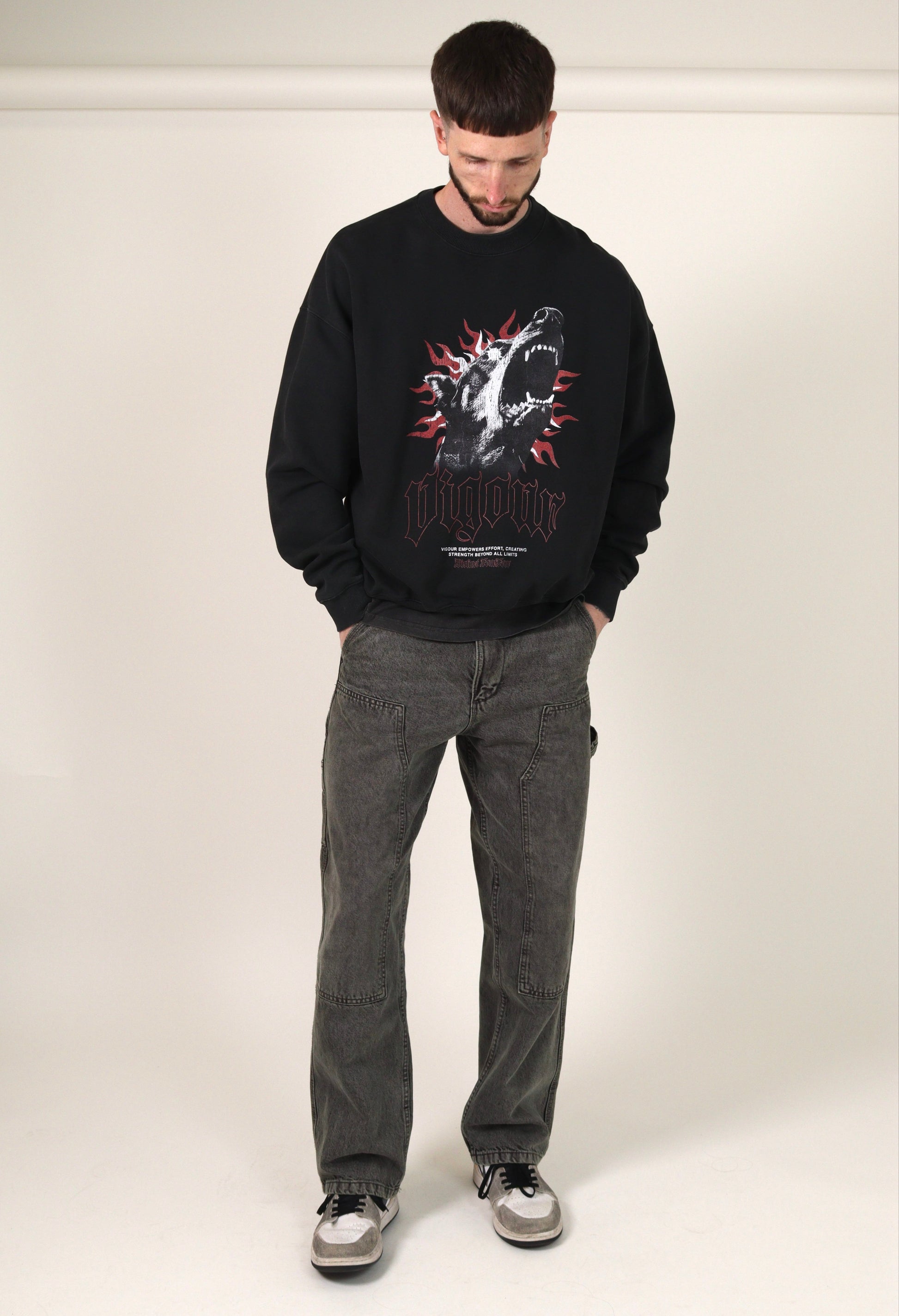 Person wearing a  vintage black sweatshirt with a graphic design and grey jeans on a white background